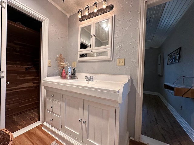 bathroom with vanity, ornamental molding, and hardwood / wood-style flooring