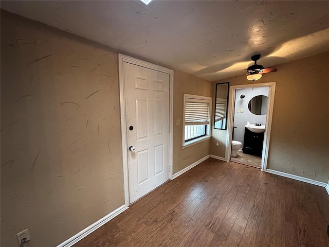 unfurnished bedroom featuring ensuite bath, ceiling fan, sink, and hardwood / wood-style flooring