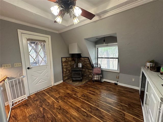 entryway featuring dark hardwood / wood-style flooring, a wood stove, ceiling fan, and crown molding