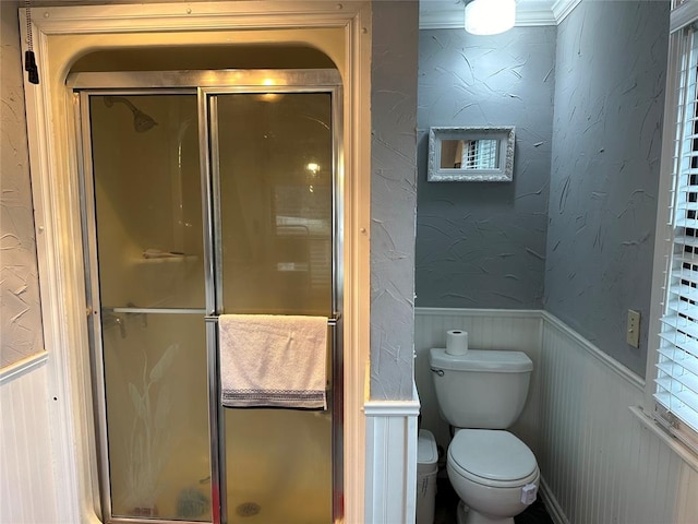 bathroom featuring ornamental molding, a shower with shower door, and toilet