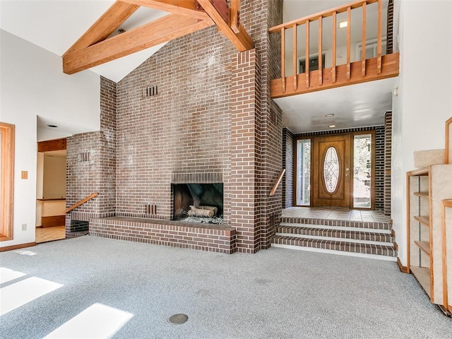 carpeted living room featuring beamed ceiling, high vaulted ceiling, a fireplace, and brick wall