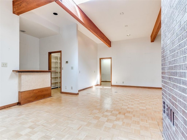 empty room with beamed ceiling, light parquet flooring, and a high ceiling