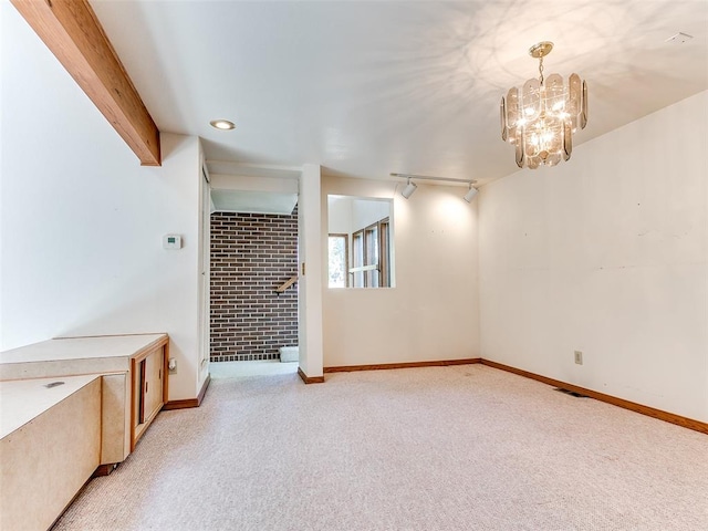 unfurnished room with light carpet, beam ceiling, track lighting, and a notable chandelier