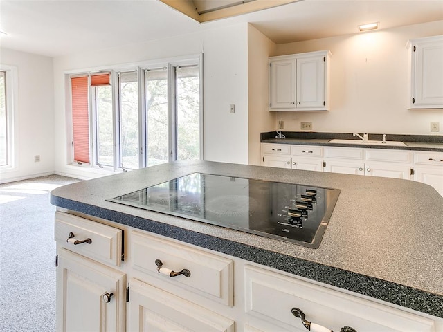 kitchen with white cabinetry, light colored carpet, black electric cooktop, and sink