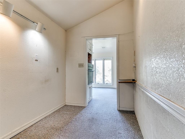 corridor with light colored carpet and vaulted ceiling