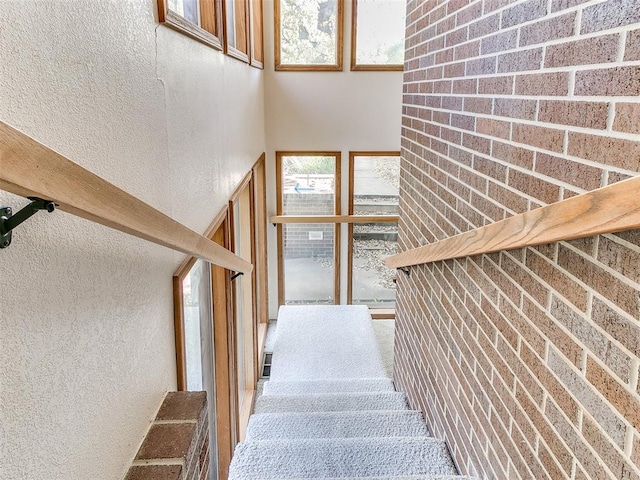 staircase with a towering ceiling and brick wall