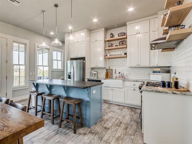 kitchen with sink, a kitchen island, stainless steel refrigerator with ice dispenser, light hardwood / wood-style floors, and white cabinets