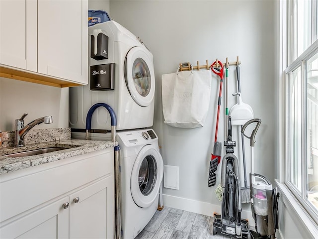 washroom with light hardwood / wood-style flooring, cabinets, sink, and stacked washer and clothes dryer