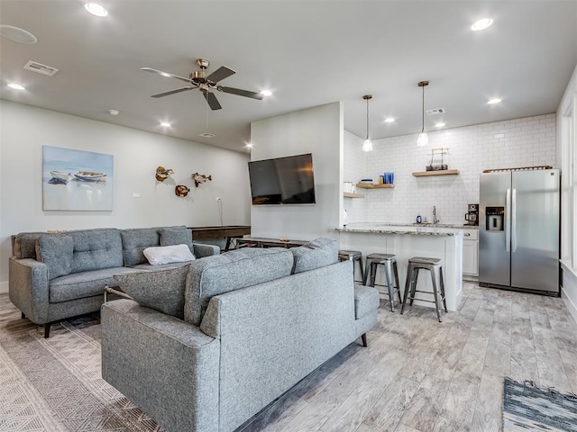 living room with ceiling fan, sink, and light hardwood / wood-style flooring