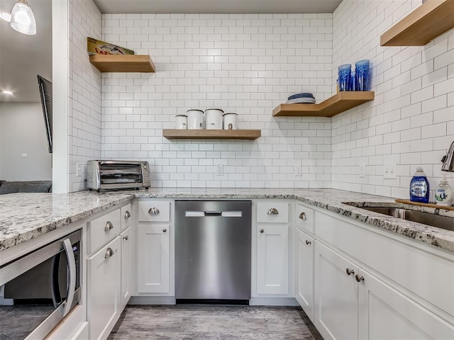 kitchen with light stone countertops, white cabinetry, sink, and appliances with stainless steel finishes