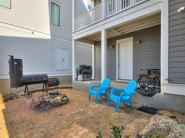 view of patio featuring grilling area, a balcony, and a fire pit