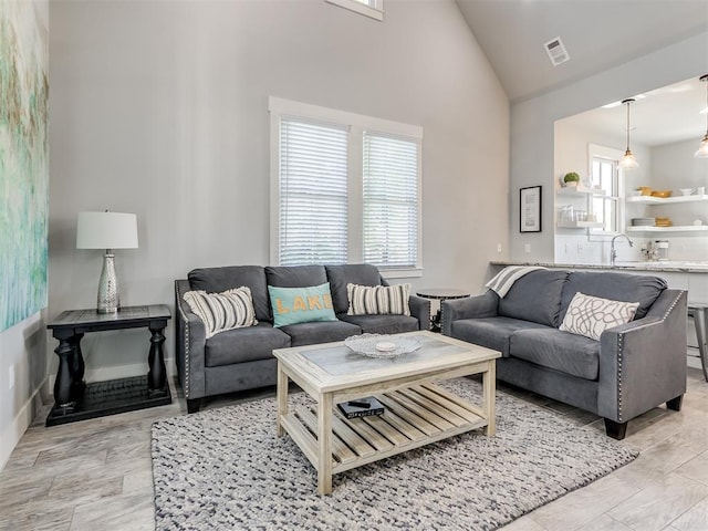 living room featuring sink and high vaulted ceiling