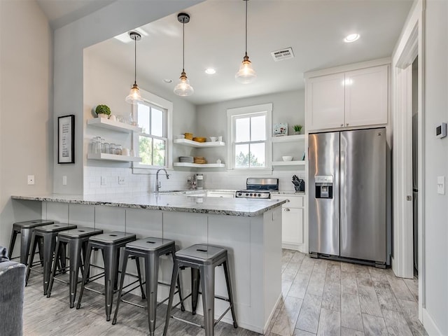 kitchen featuring white cabinets, kitchen peninsula, appliances with stainless steel finishes, and light hardwood / wood-style flooring