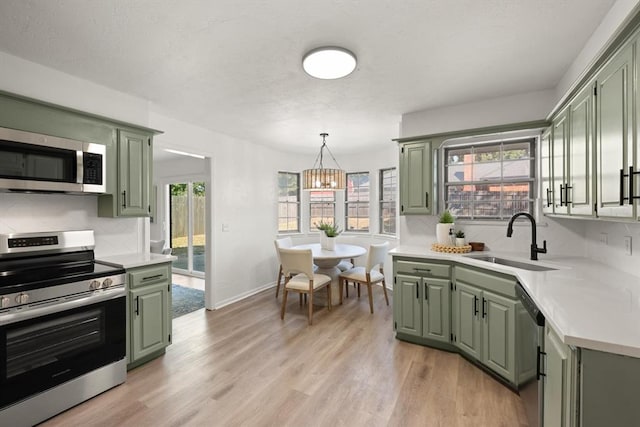 kitchen with stainless steel appliances, green cabinetry, and sink