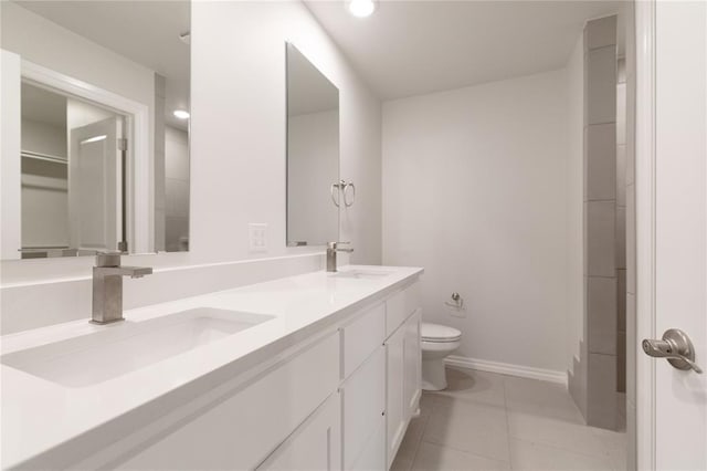 bathroom with double vanity, a sink, toilet, and tile patterned floors