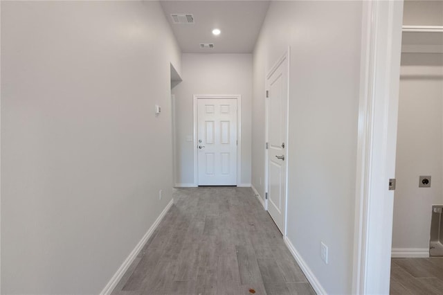 corridor with wood finished floors, visible vents, and baseboards