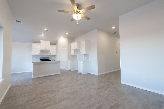 kitchen featuring visible vents, decorative backsplash, ceiling fan, open floor plan, and stainless steel range with electric cooktop