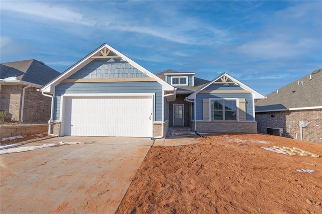 craftsman inspired home with concrete driveway, central AC, brick siding, and an attached garage