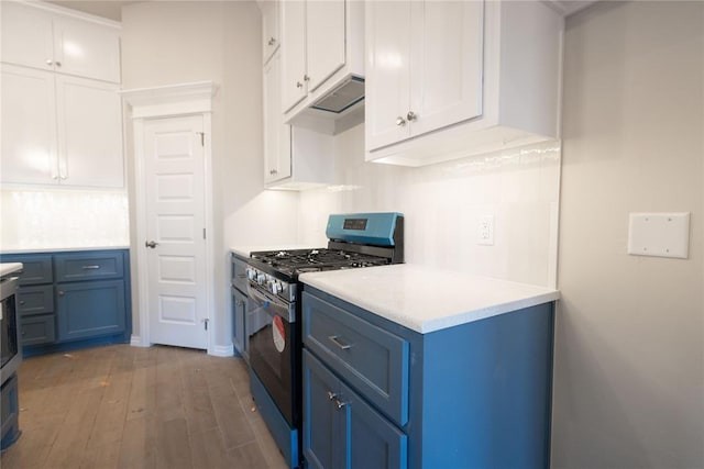 kitchen with blue cabinets, light countertops, white cabinetry, and stainless steel gas range oven