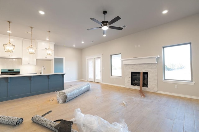 living area with a stone fireplace, light wood-type flooring, visible vents, and recessed lighting