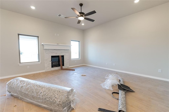 living area featuring a fireplace, light wood finished floors, recessed lighting, visible vents, and baseboards