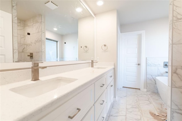 bathroom with a freestanding bath, marble finish floor, double vanity, and a sink