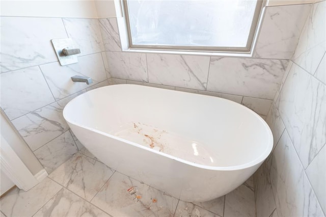 full bath with marble finish floor and a freestanding bath