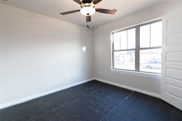 spare room with ceiling fan, baseboards, and dark colored carpet