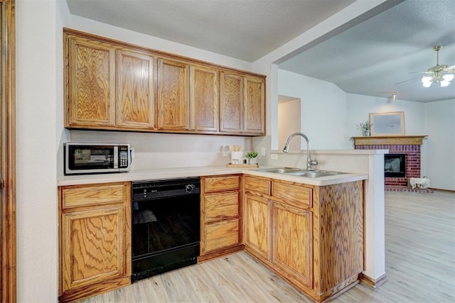 kitchen with dishwasher, light hardwood / wood-style floors, a brick fireplace, and sink