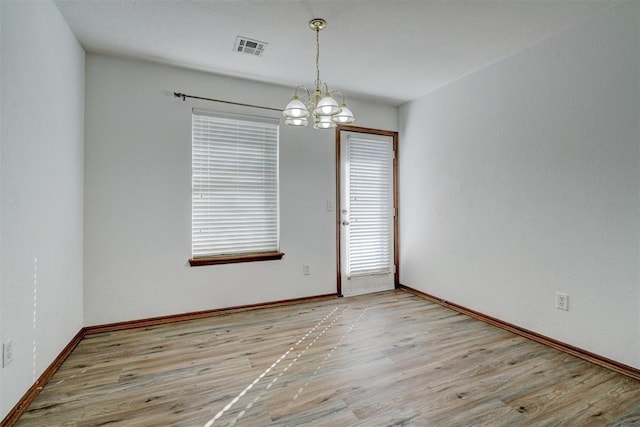 empty room with a chandelier and light wood-type flooring