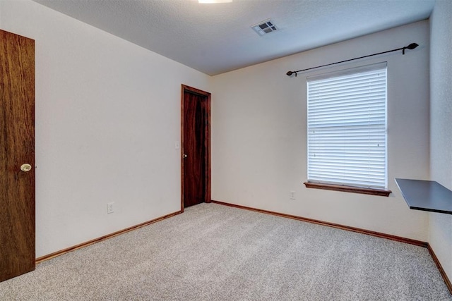 spare room featuring a textured ceiling and light carpet