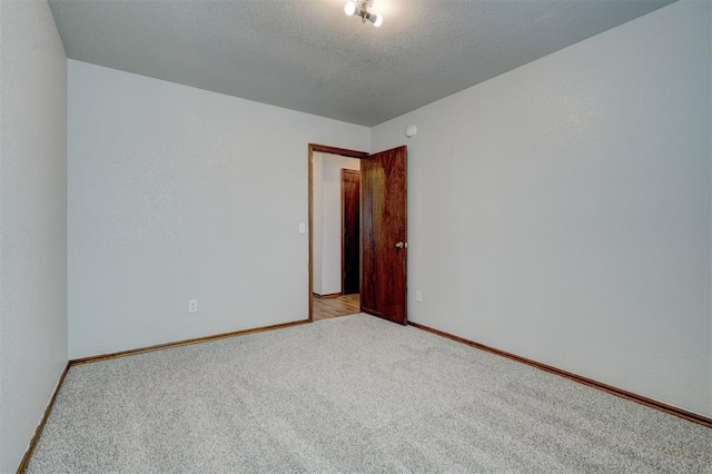 empty room with light carpet and a textured ceiling