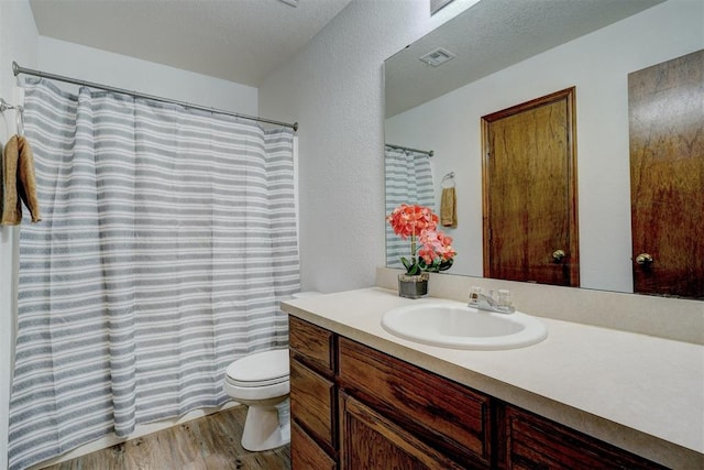 bathroom featuring vanity, toilet, wood-type flooring, and a textured ceiling