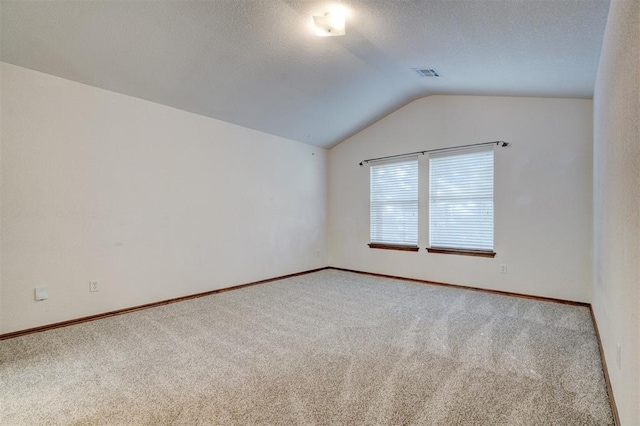 carpeted spare room featuring a textured ceiling and vaulted ceiling