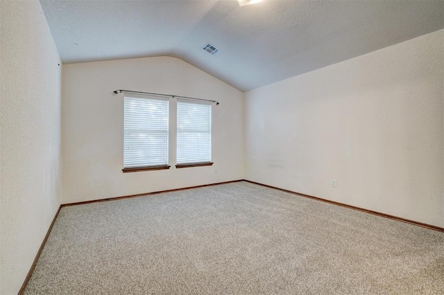 carpeted empty room with a textured ceiling and vaulted ceiling