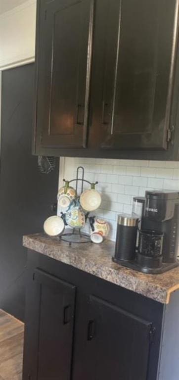 room details featuring decorative backsplash, dark brown cabinets, and light stone countertops