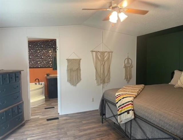 bedroom featuring ceiling fan, vaulted ceiling, wood-type flooring, and ensuite bath