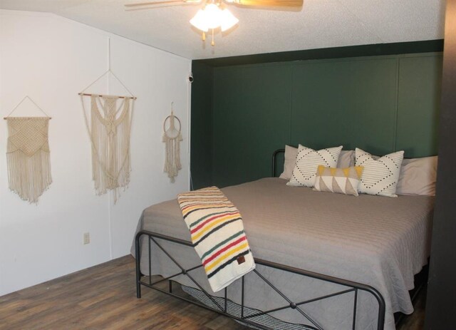 bedroom featuring a textured ceiling, ceiling fan, dark wood-type flooring, and lofted ceiling