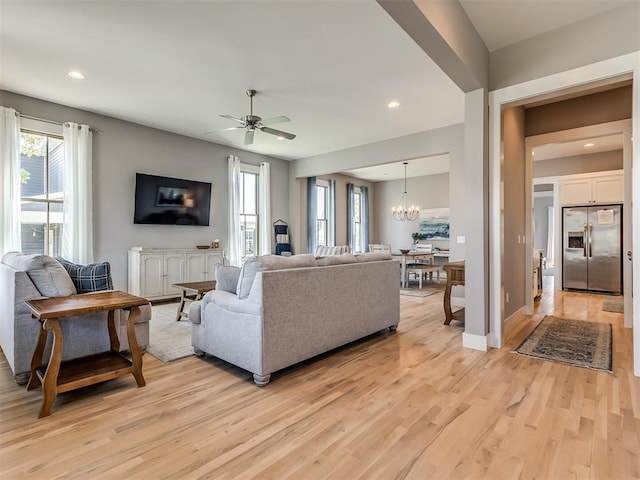 living room with light hardwood / wood-style flooring and ceiling fan with notable chandelier