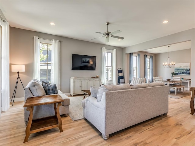 living room with ceiling fan with notable chandelier and light wood-type flooring