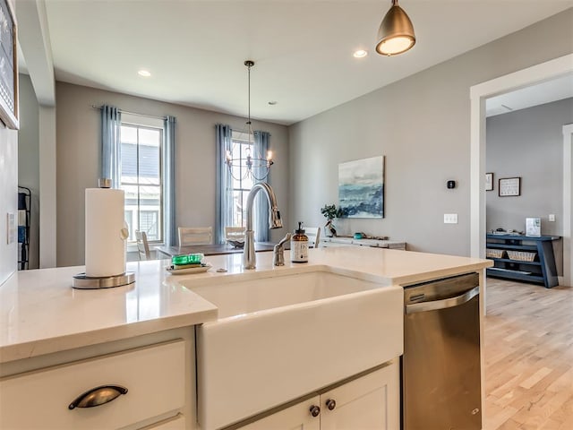 kitchen with decorative light fixtures, light hardwood / wood-style floors, stainless steel dishwasher, and sink