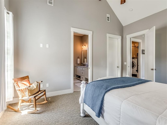 carpeted bedroom with connected bathroom, washer / clothes dryer, and high vaulted ceiling