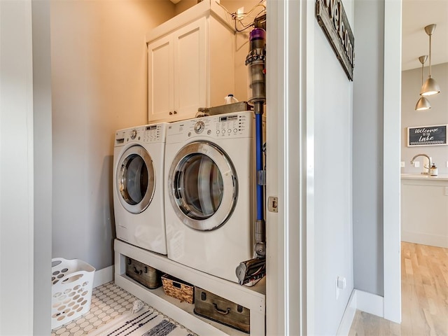 laundry area featuring cabinets, sink, light hardwood / wood-style flooring, and washing machine and clothes dryer