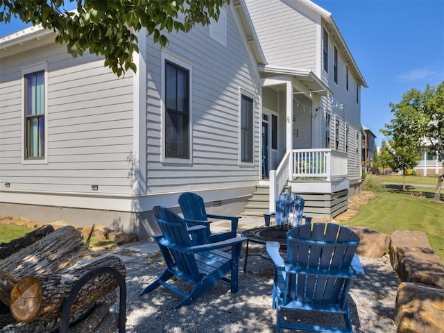 back of house with a lawn and an outdoor fire pit