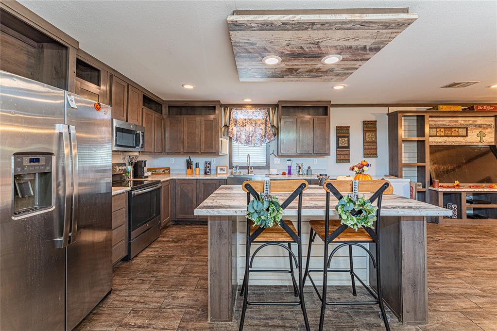 kitchen with sink, a center island, a kitchen breakfast bar, a tray ceiling, and appliances with stainless steel finishes