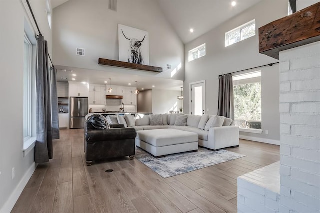 living room featuring light hardwood / wood-style floors, sink, and high vaulted ceiling