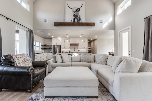 living room featuring light hardwood / wood-style flooring, a towering ceiling, and plenty of natural light