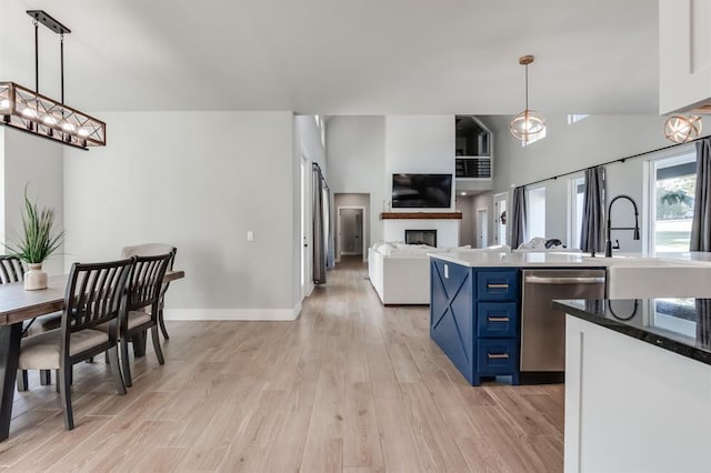 kitchen with blue cabinetry, pendant lighting, light wood-type flooring, and stainless steel dishwasher