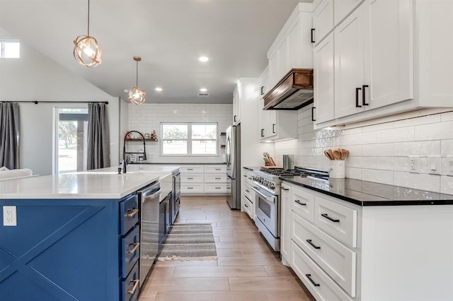 kitchen with plenty of natural light, appliances with stainless steel finishes, pendant lighting, and blue cabinets