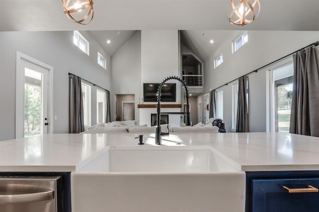 kitchen featuring high vaulted ceiling, blue cabinets, sink, and hanging light fixtures